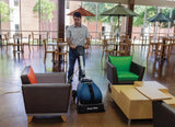 Man operating the Powr-Flite CAS16 compact cylindrical brush scrubber in a cafeteria or waiting area, effectively cleaning the floor and maintaining a hygienic environment in high-traffic areas